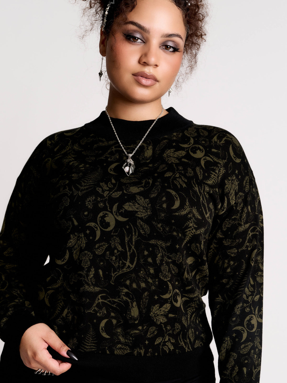a black long-sleeve top with an intricate olive green forest findings pattern