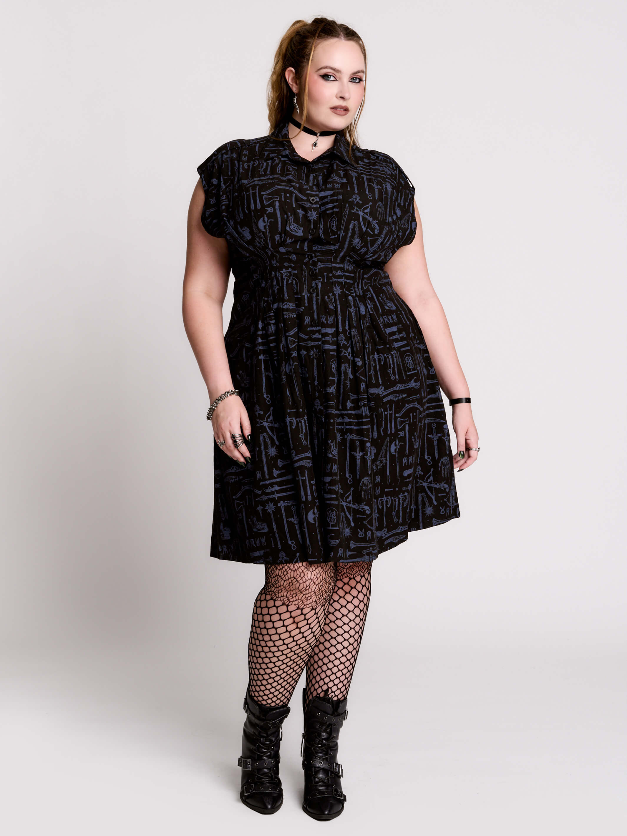 a button-front shirt dress featuring a striking medieval-inspired print with weaponry and macabre motifs.