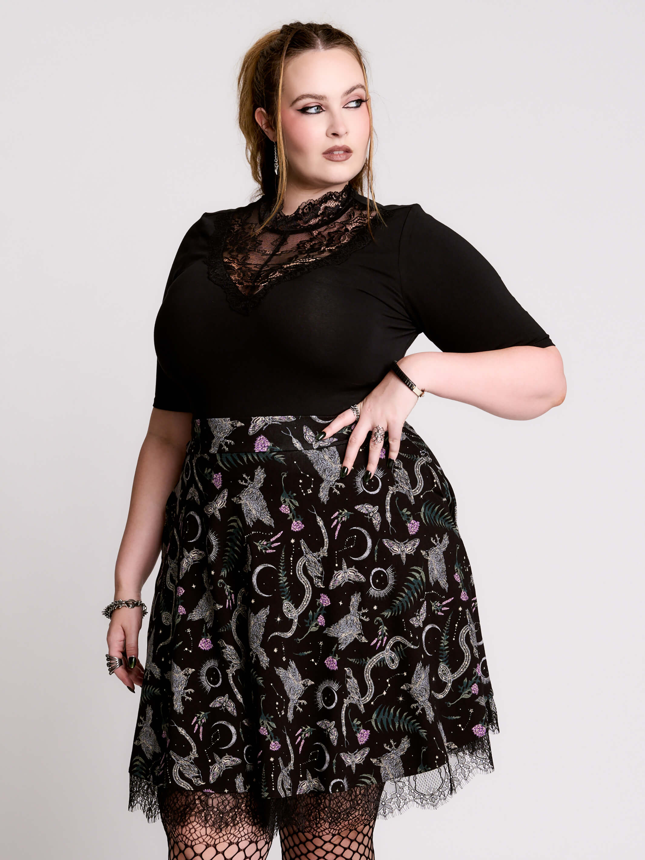 A black flared skirt featuring a gray and purple gothic print with lace hem.