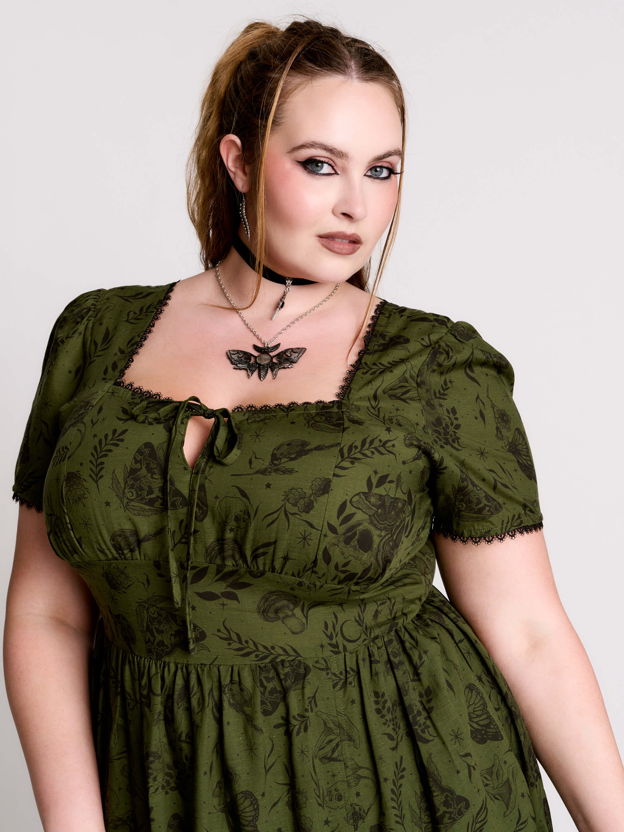 a short-sleeved olive green midi dress with a gothic pattern
