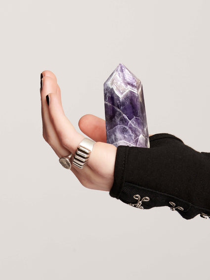 a hand holding a purple crystal