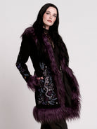 This mid-length black coat pairs a soft, suede-like finish with plush amethyst-purple faux fur trim
