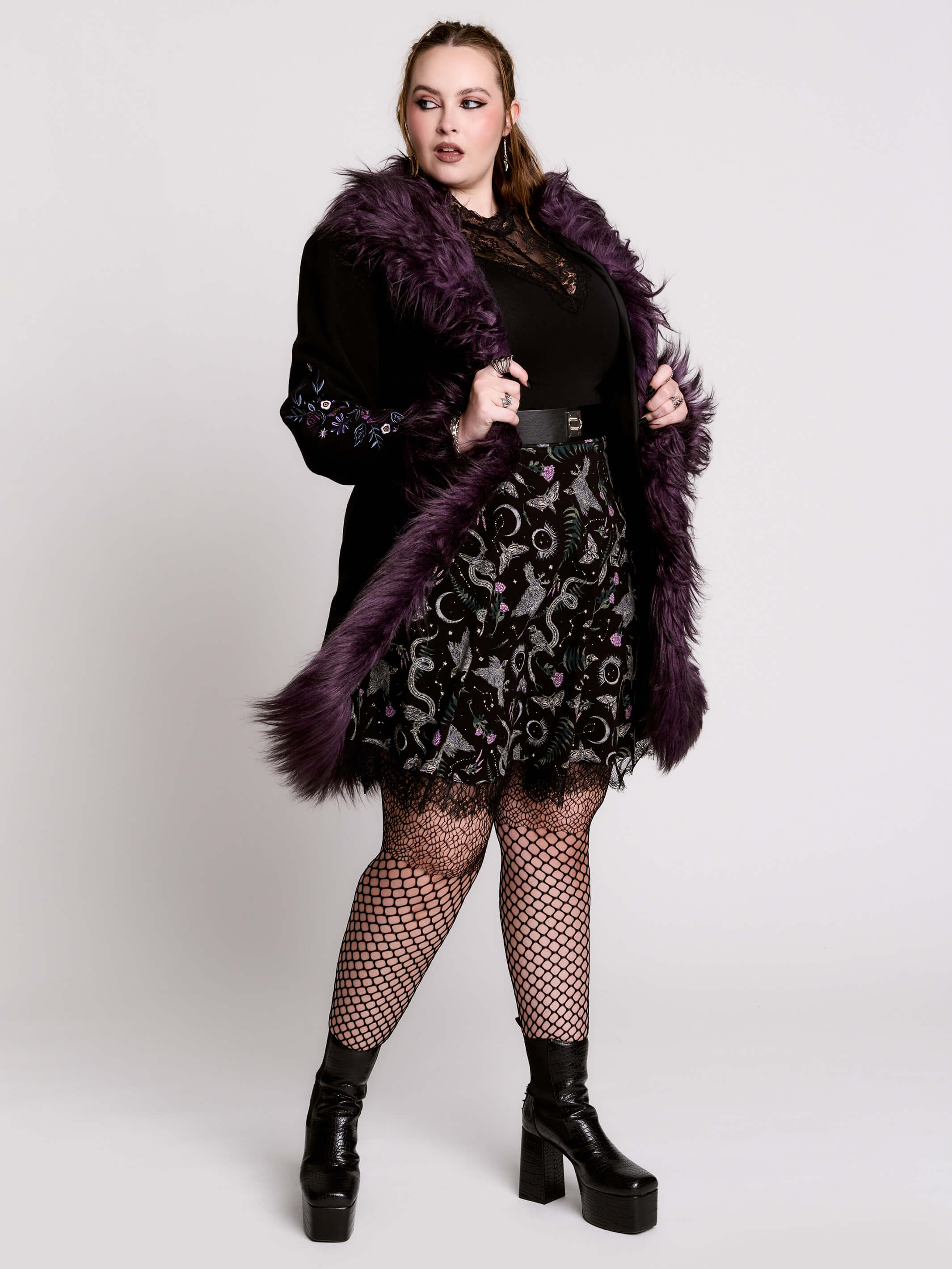 This mid-length black coat pairs a soft, suede-like finish with plush amethyst-purple faux fur trim