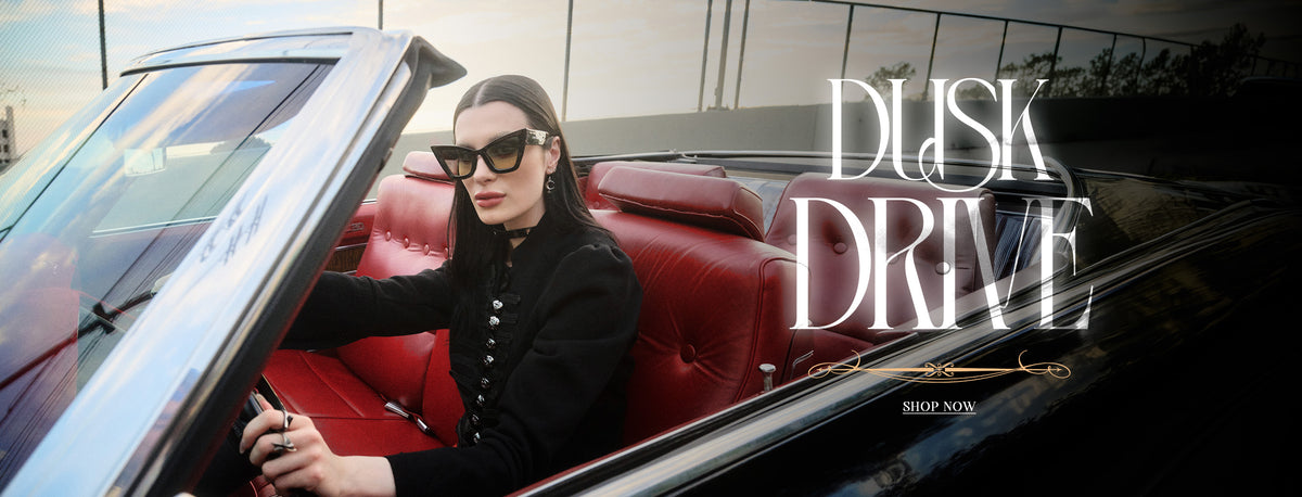 A woman wearing black sunglasses and a black jacket sits in a red leather convertible car, with the title text 'DUSK DRIVE' 