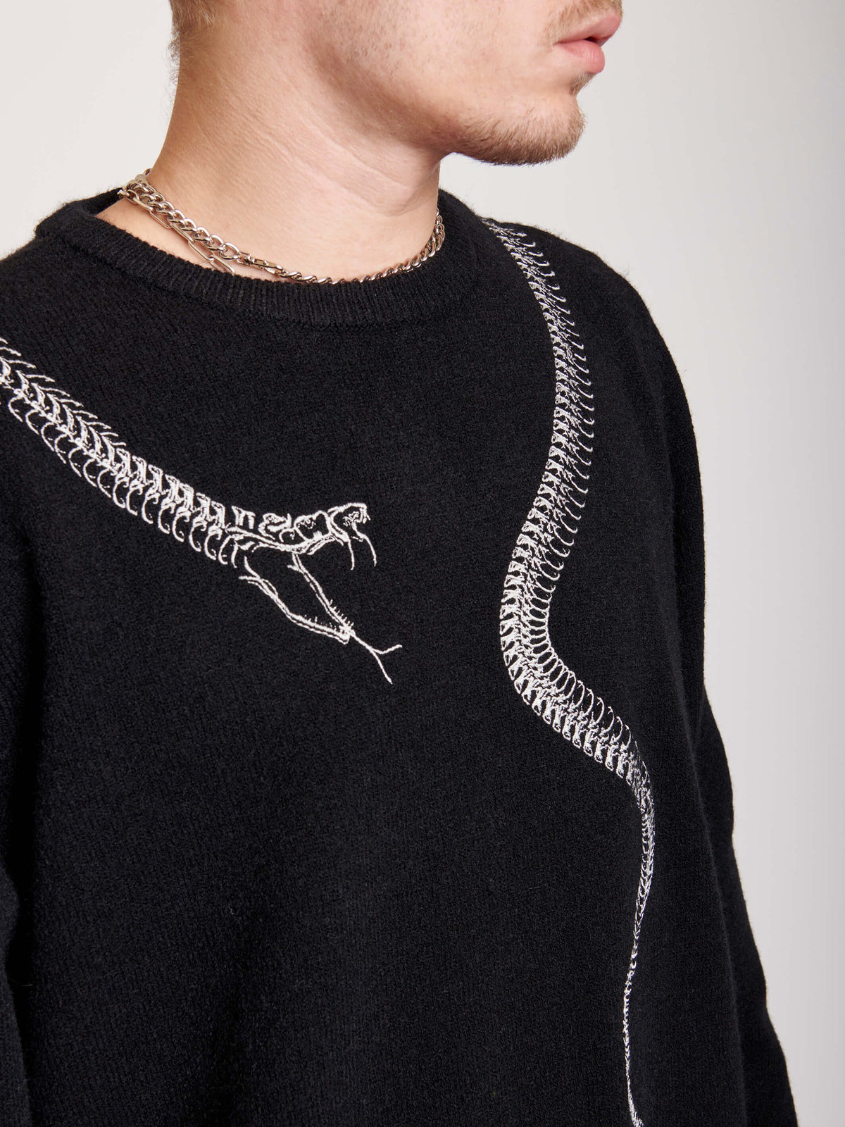 sweater with skeleton snake detail around neck.