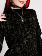 a black long-sleeve top with an intricate olive green forest findings pattern