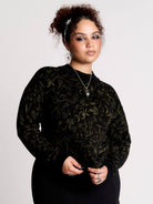 a black long-sleeve top with an intricate olive green forest findings pattern