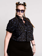 Armory Cropped Shirt is a boxy, cropped, short-sleeve button-down that mixes crisp classic shirting with dark, gothic illustration. 