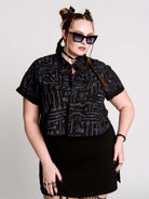 Armory Cropped Shirt is a boxy, cropped, short-sleeve button-down that mixes crisp classic shirting with dark, gothic illustration. 
