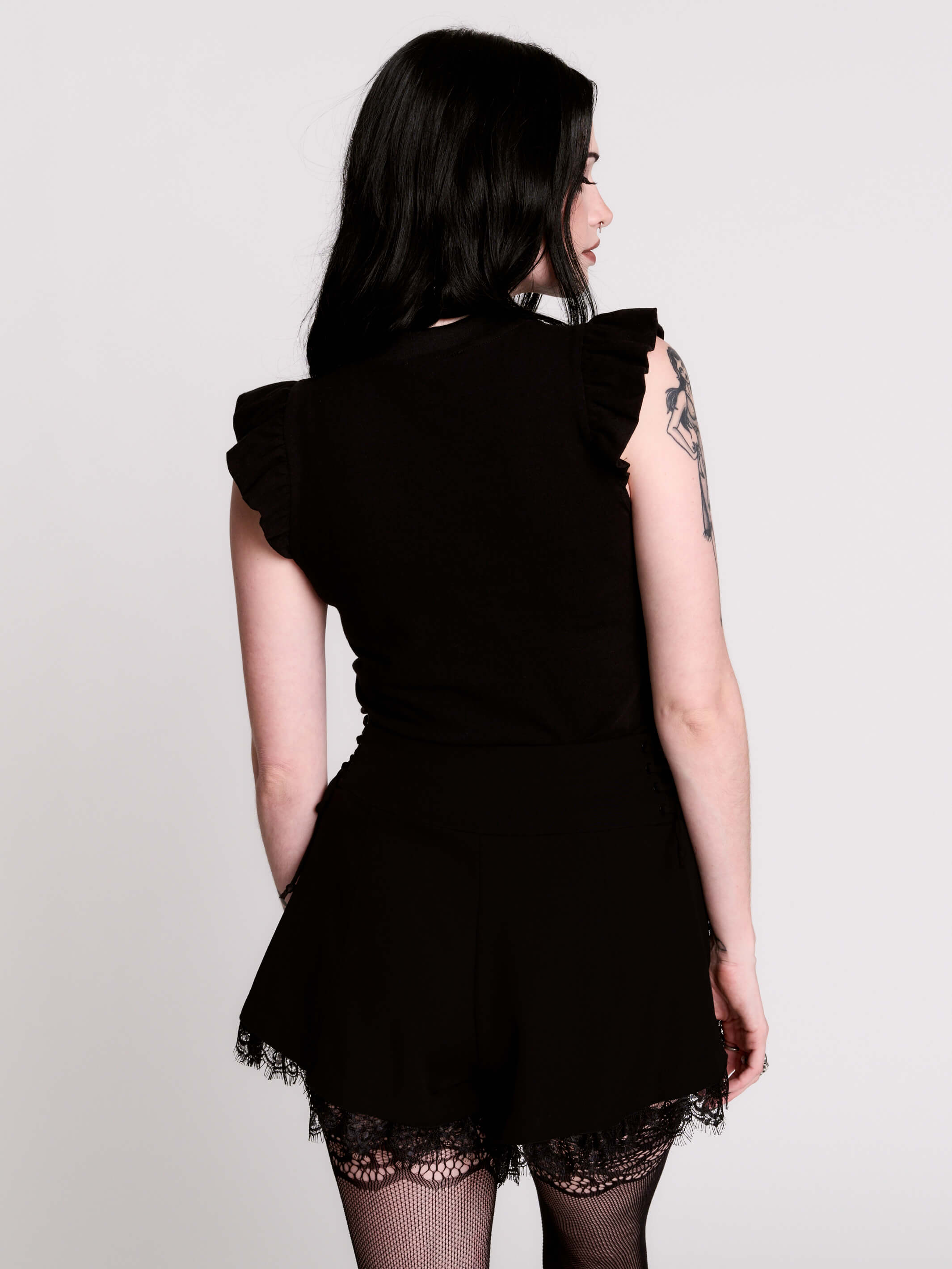 A black ruffled sleeveless top with a sheer chest cutout.