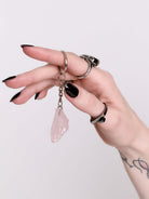 A silver keychain featuring a raw pink crystal pendant.