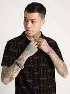 A black short-sleeve button-up shirt with  repeating red and green scarab beetle pattern.