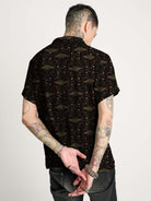 A black short-sleeve button-up shirt with  repeating red and green scarab beetle pattern.
