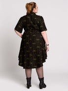 a short-sleeved high-low dress in black with a small red and green floral pattern.