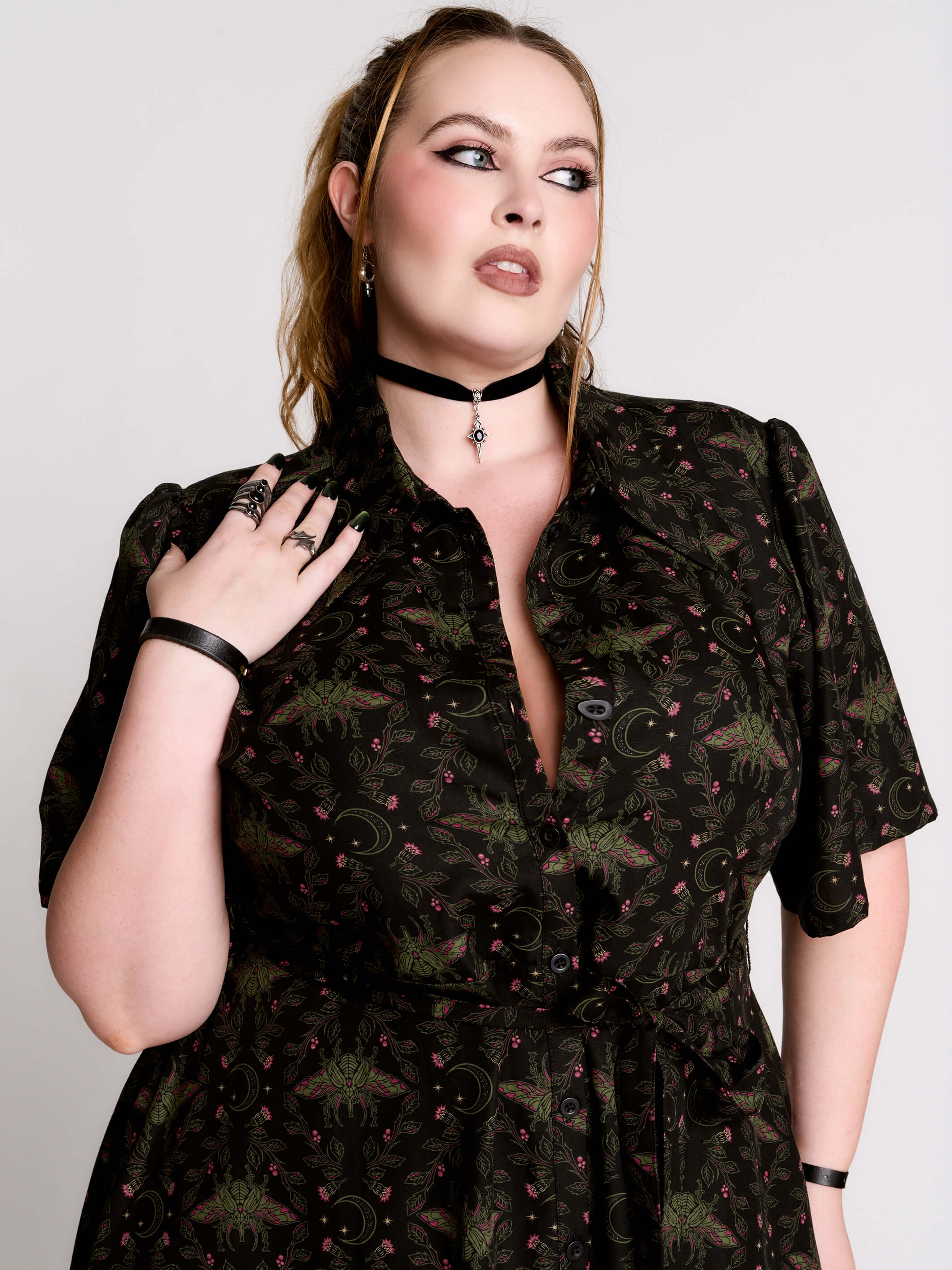 a short-sleeved high-low dress in black with a small red and green floral pattern.