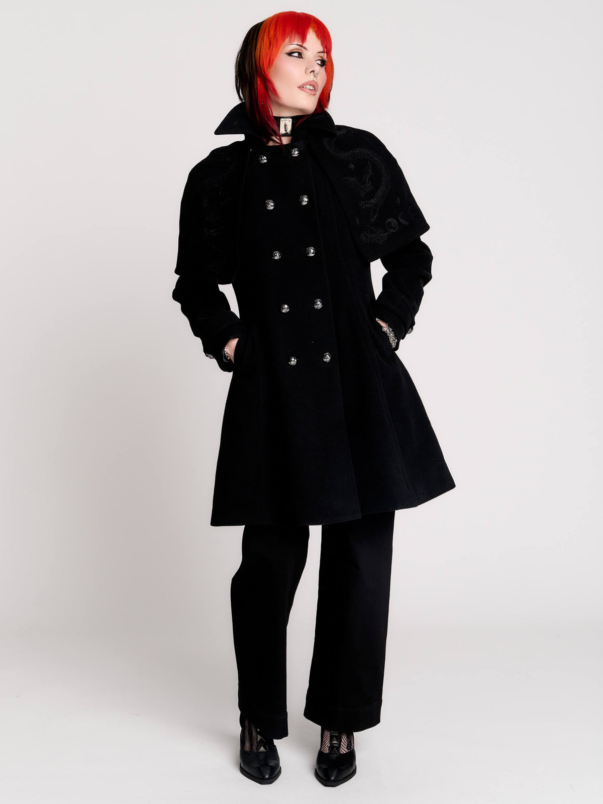 a black double-breasted coat with silver buttons and gothic dragon embroidery on the shoulder cape