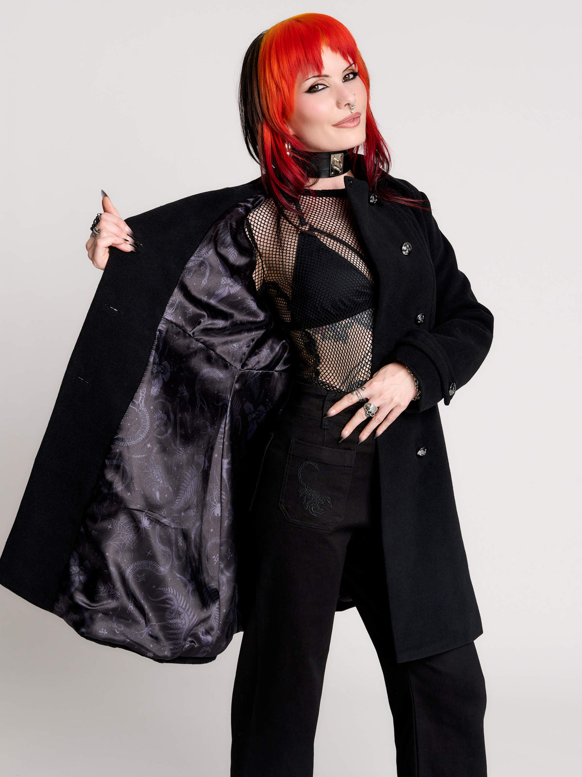 a black double-breasted coat with silver buttons and gothic dragon embroidery on the shoulder cape