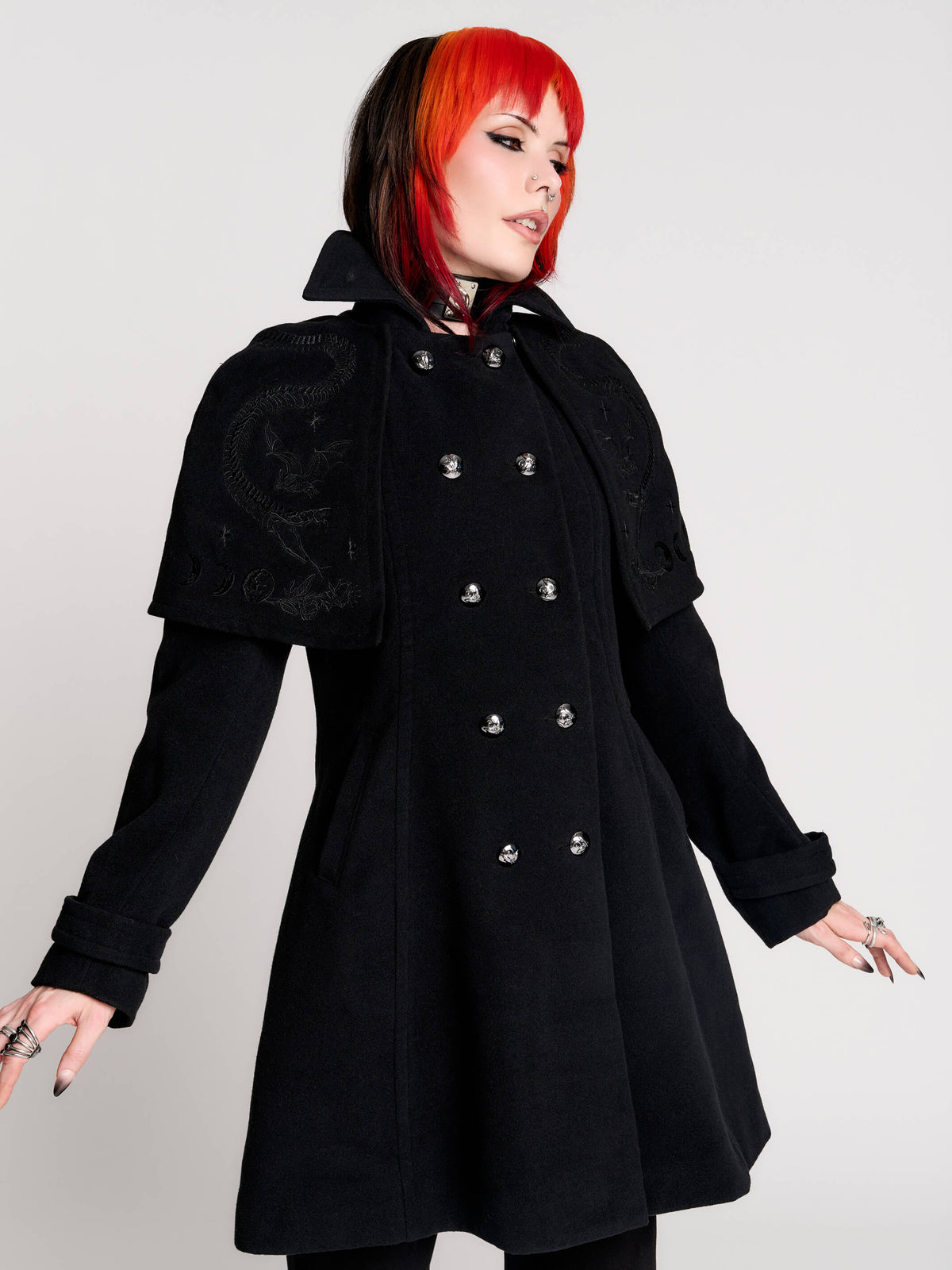 a black double-breasted coat with silver buttons and gothic dragon embroidery on the shoulder cape