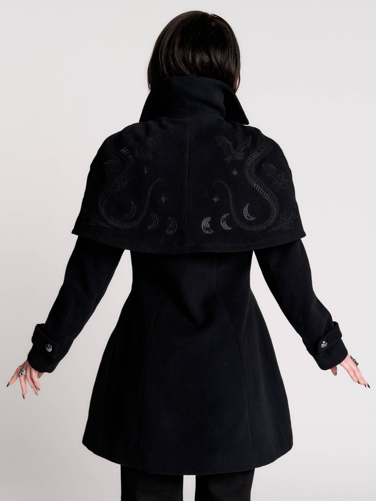 a black double-breasted coat with silver buttons and gothic dragon embroidery on the shoulder cape