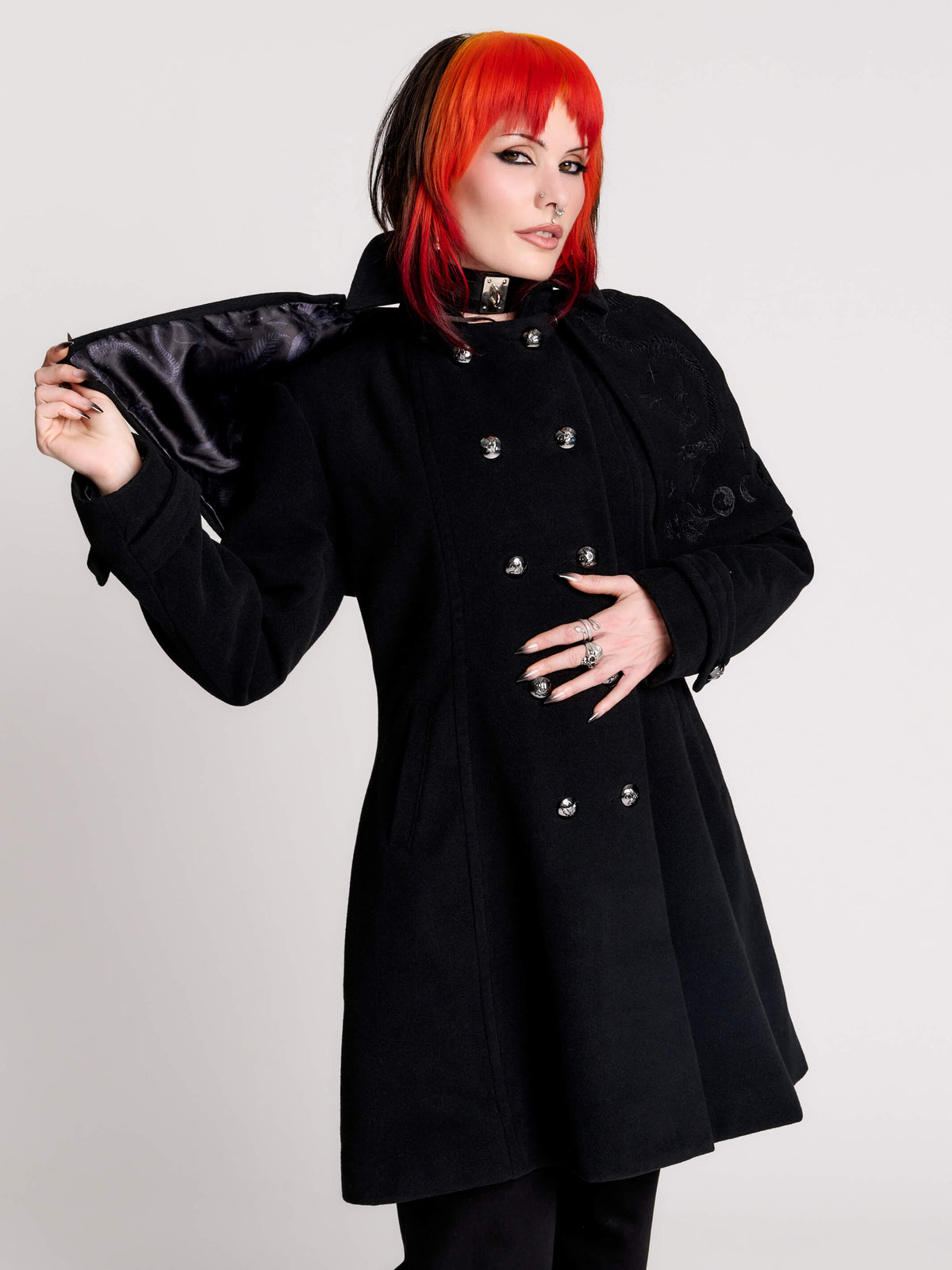 a black double-breasted coat with silver buttons and gothic dragon embroidery on the detachable shoulder cape