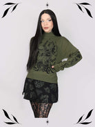 an olive green mock-neck sweater featuring a black gothic graphic