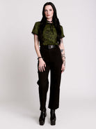 a short-sleeve olive green blouse with a dark botanical pattern, black lace trim collar with black ribbon tiedetail and black buttons. 