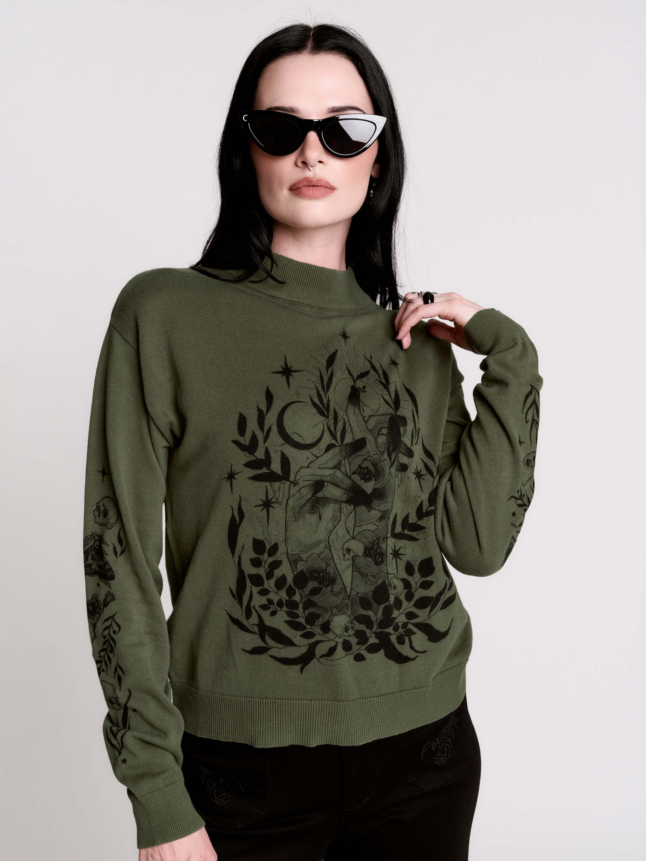 an olive green mock-neck sweater featuring a black gothic graphic