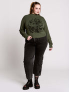 an olive green mock-neck sweater featuring a black gothic graphic