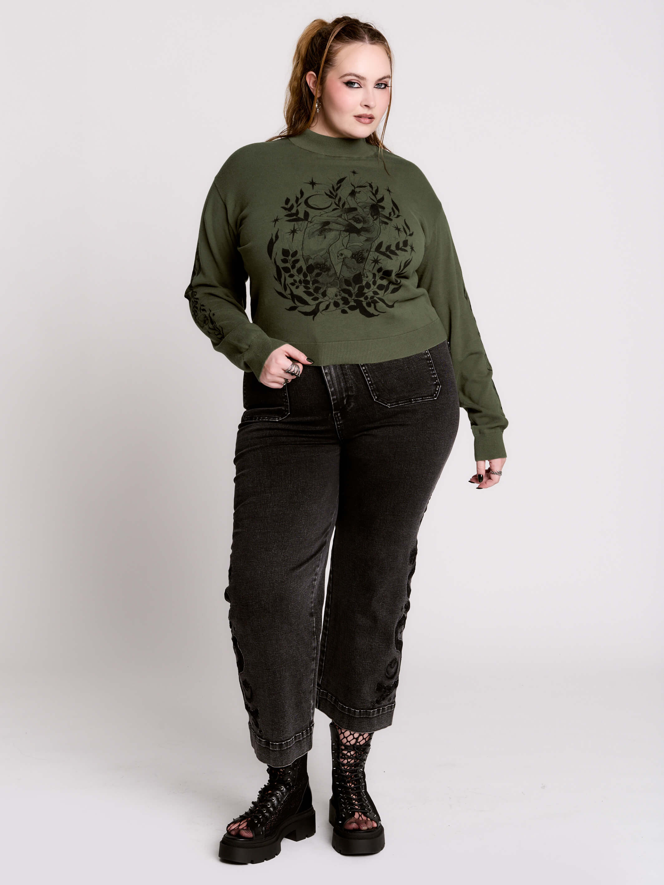 an olive green mock-neck sweater featuring a black gothic graphic