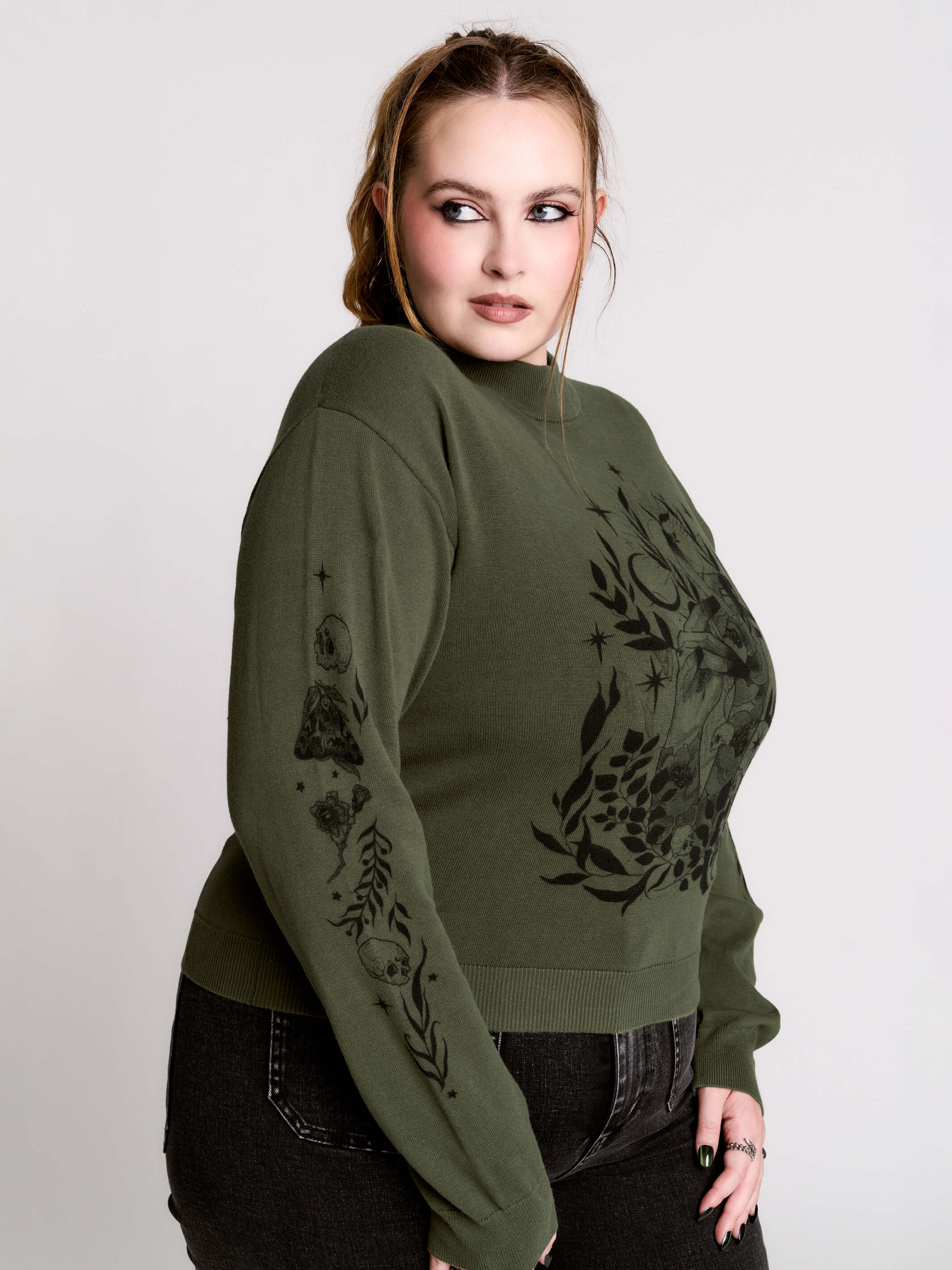 an olive green mock-neck sweater featuring a black gothic graphic