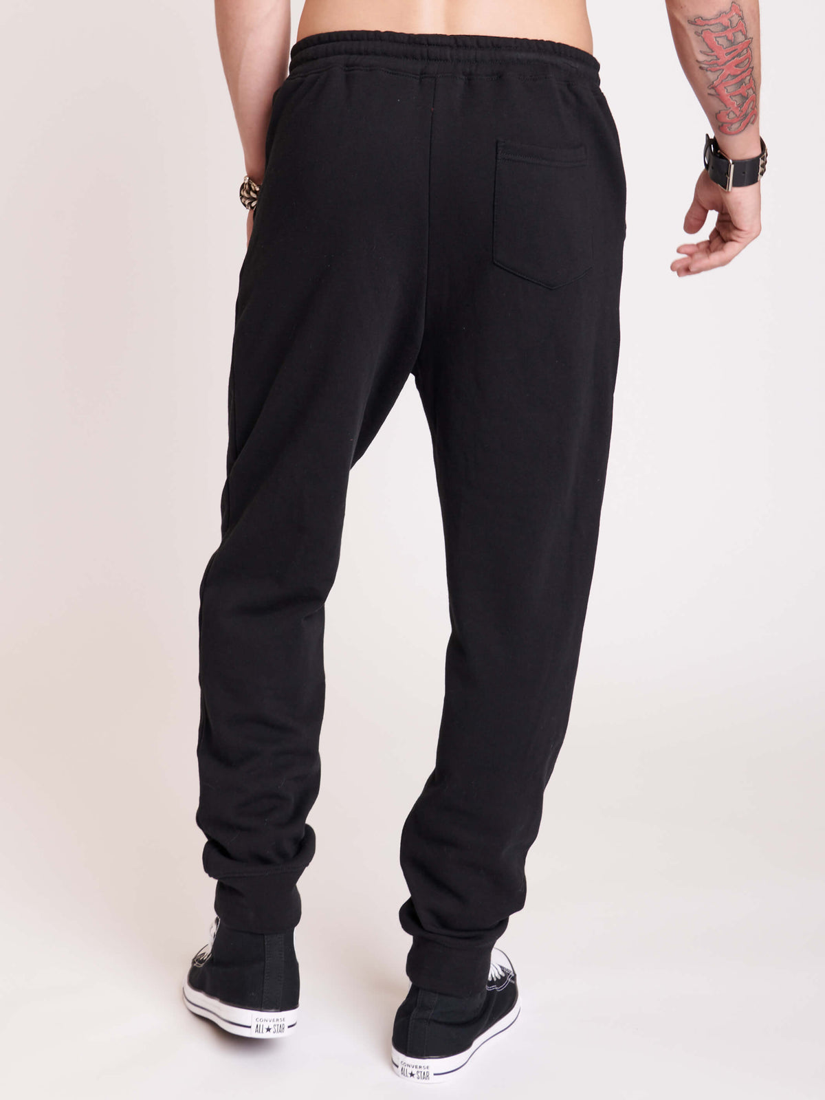 Black joggers with white dagger graphic from thighs to shins
